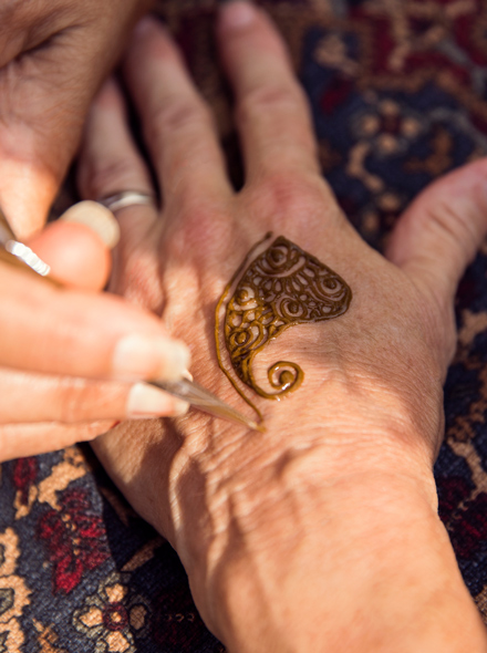 Close das m?os de uma pessoa fazendo tatuagem de henna nas m?os de outra pessoa.