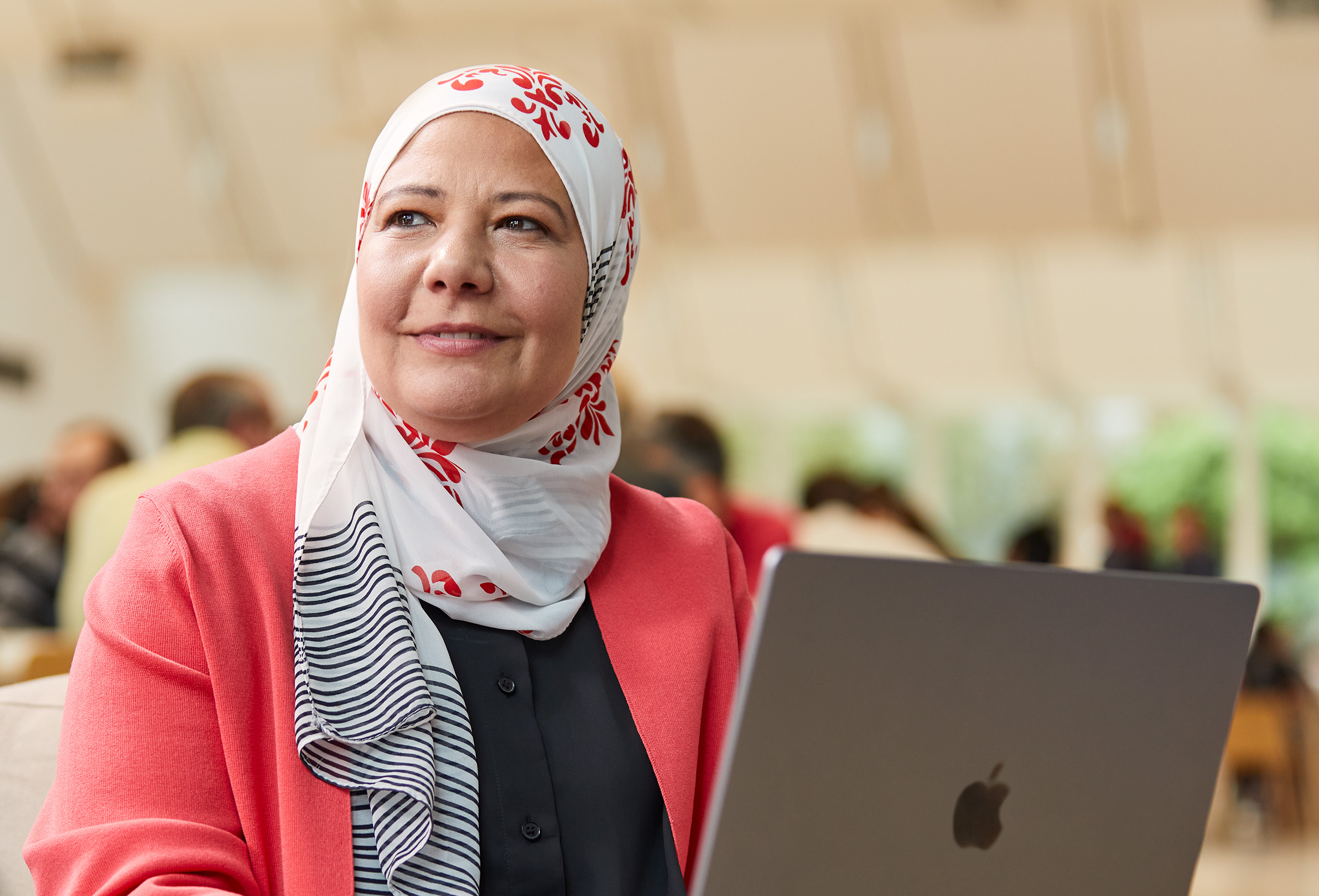 Egy ül?, oldalra néz? Apple-alkalmazott, aki egy MacBookon dolgozik.