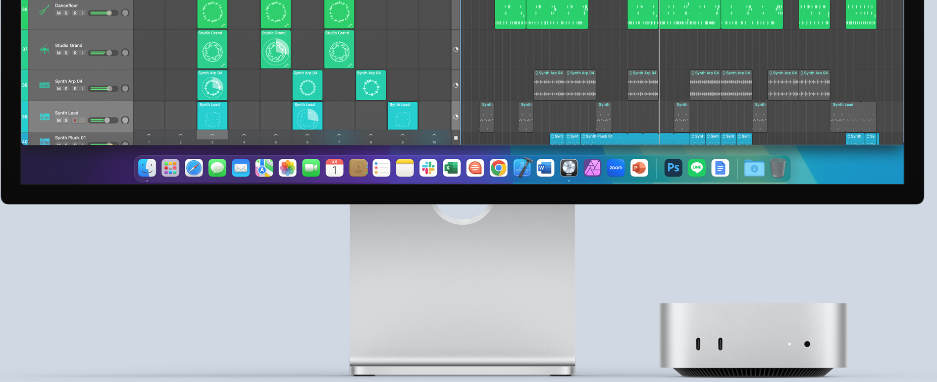前面のポートとインジケータランプが見えている、シルバーのMac miniの前面。カラフルな畫面と、Dockに様々なアプリのアイコンが表示されたMacのモニタの下に収まっている