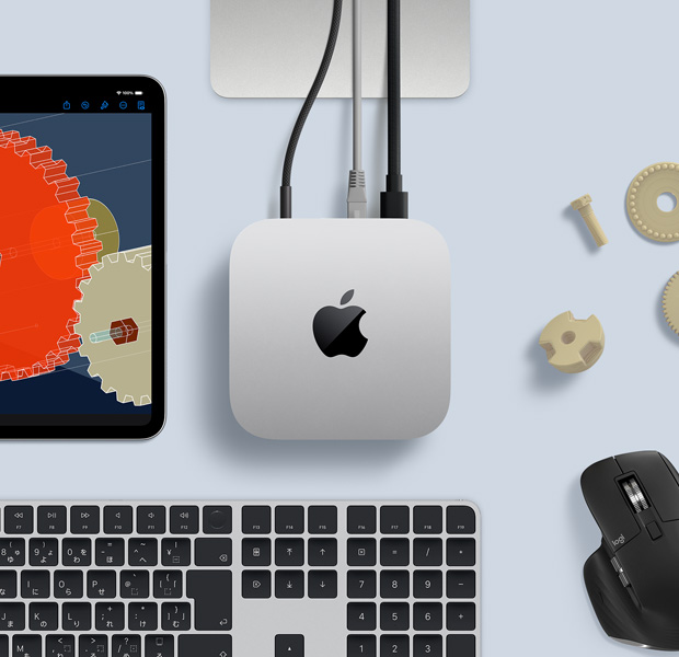 デスク上に置かれたシルバーのMac miniを上から見た図。ブラックとシルバーのワイヤレスキーボード、ブラックのワイヤレスマウス、iPadが一緒に配置されている