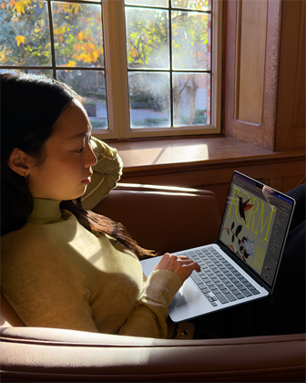 ?mogus, s?dintis ant k?d?s, naudojasi ?MacBook Air“