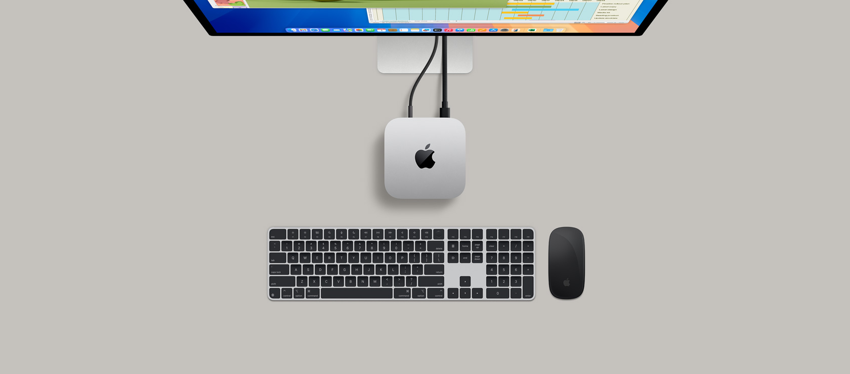 俯視圖展示銀色 Mac mini 連上顯示器，螢?zāi)伙@示打機(jī)場面，旁邊放有無線鍵盤、遊戲手掣和藍(lán)色 AirPods Max。