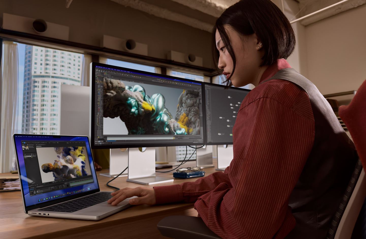 Pracuj?ca w biurze osoba u?ywa laptopa MacBook, który jest pod??czony do monitora Studio Display XDR za pomoc? portu Thunderbolt 5