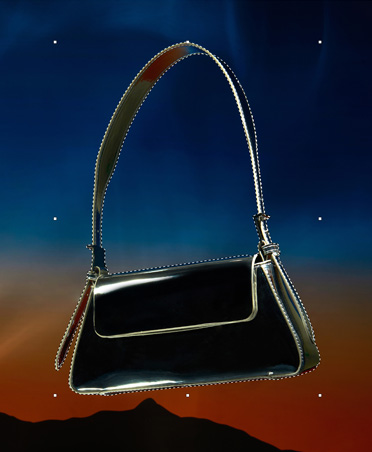 A black handbag that is outlined with dashed lines, selection tool, editing image, sunset background with silhouette of mountains